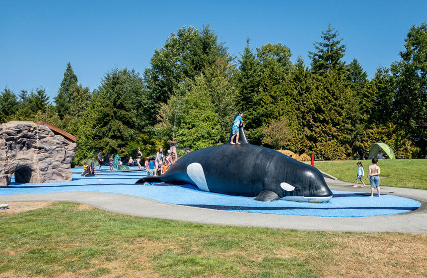 Crossroads Park Playground Big Orca Splash Park in Bellevue, one of the top Eastside splash parks outside of Seattle. Kids sliding down the front of the orca as a makeshift slide.