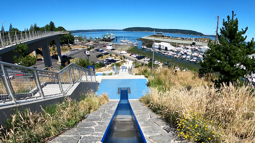 POV looking down one of the tall slides at the Stairs and Slides playground in Point Defiance Park, Tacoma. This unique and adventurous play area features a mix of staircases and slides built into a hillside, offering fun for kids and families in a natural park setting.