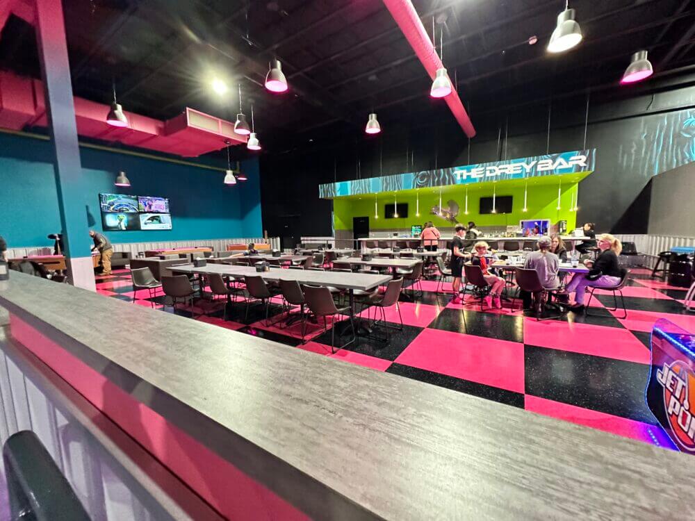The food section at Flying Squirrel Trampoline Park features spacious tables where families can take a break and enjoy snacks or a meal. With a kid-friendly menu offering pizza, drinks, and other treats, this dining area provides a convenient spot to refuel after hours of jumping fun.
