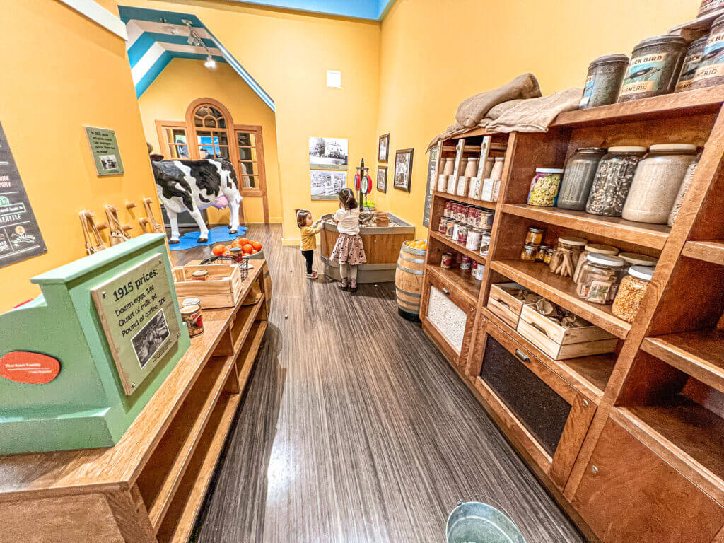 The Fancy Groceries exhibit at KidsQuest Children’s Museum in Bellevue offers a delightful twist on the classic pretend play grocery store. Styled as an old-fashioned mercantile, it combines the familiar elements of shopping—like baskets, shelves of play food, and a checkout counter—with historical touches that give kids a sense of life in a past era. Young visitors can shop for ‘groceries,’ stock the shelves, and take turns being the customer or the cashier. It’s a perfect setting for siblings to play together—like big brother showing little sister how to shop—while learning early math skills, cooperation, and storytelling. This exhibit is a favorite among families for encouraging creativity, role-play, and social interaction