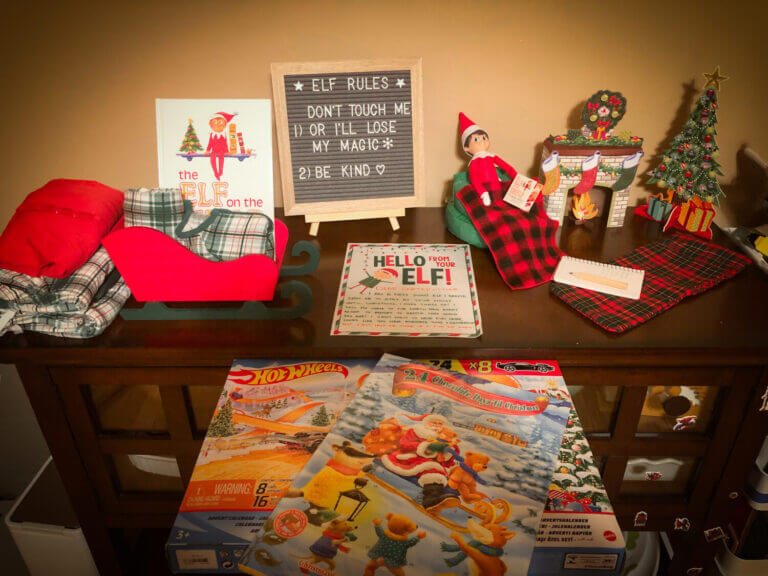 Elf on the Shelf Welcome, sitting on the counter top with an advent calendar and the Elf Rules of "Don't touch me or I'll lose my magic" and "Be Kind"