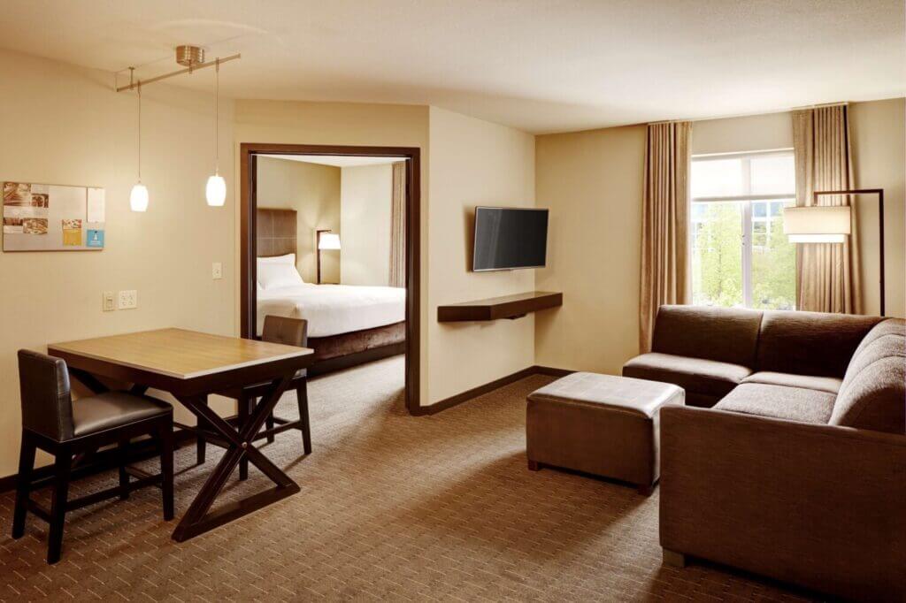 One-bedroom suite at Hyatt House Bellevue featuring a spacious living room with sofa and TV, perfect for families who want extra space to relax during their stay.