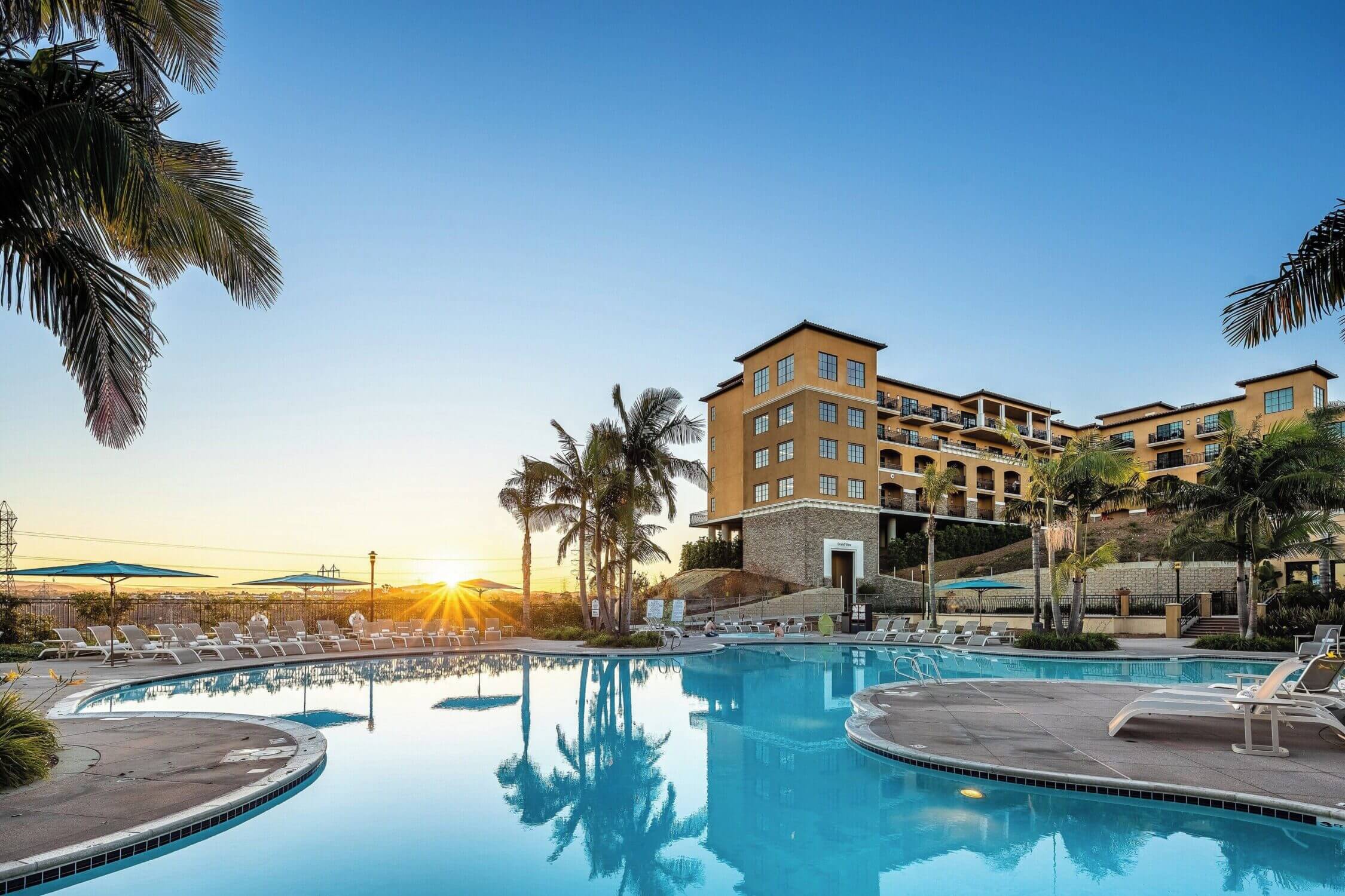 Westin Carlsbad Resort & Spa outdoor pool at sunset, surrounded by palm trees. A perfect family-friendly destination for visitors.