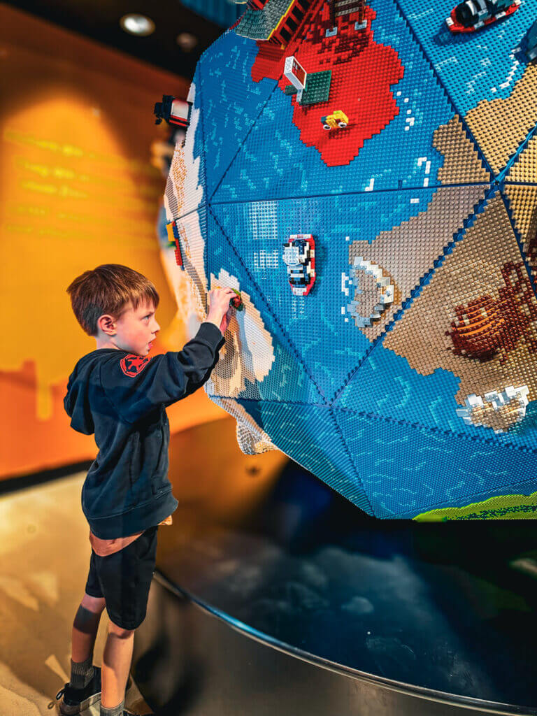Boy playing with LEGOs at LEGOLAND in Carlsbad, exploring a large interactive LEGO world.