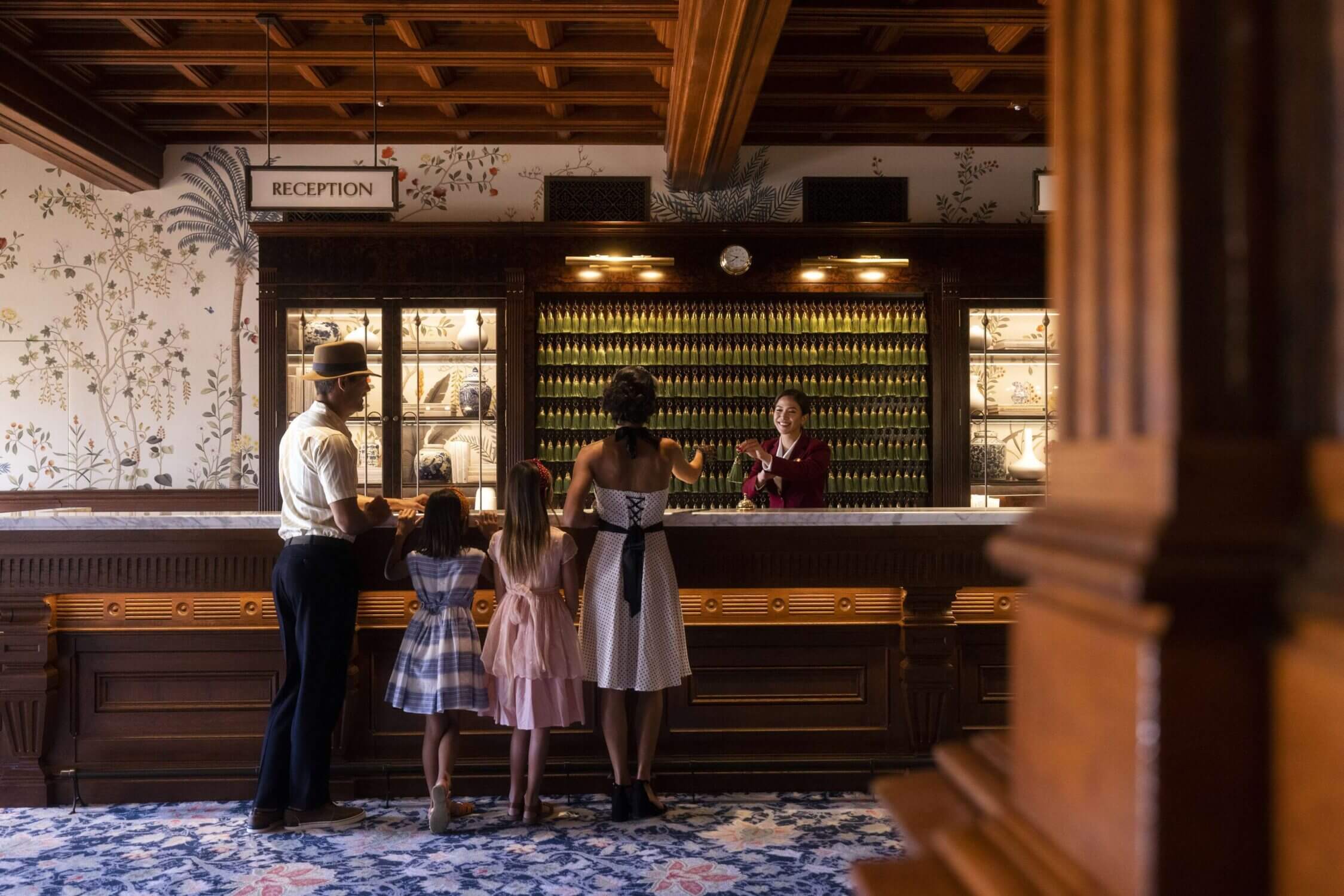 A family dressed up, with two young girls in dresses, checking in at the lobby of the famous historic Hotel del Coronado. A timeless and elegant beachfront resort in San Diego, perfect for a family vacation.