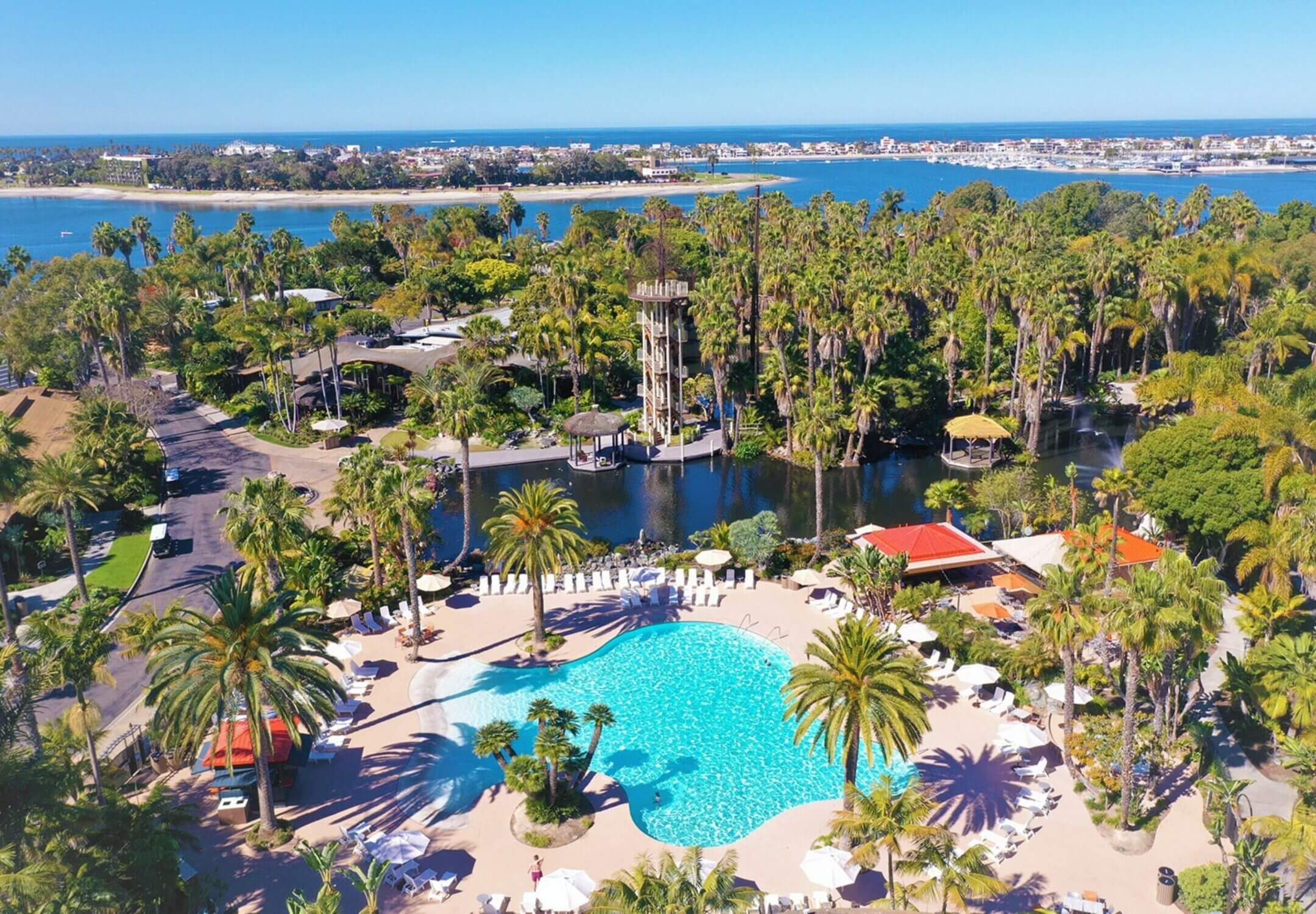 Aerial view of the pool at Paradise Point Resort in Mission Bay, San Diego, showcasing one of its five outdoor pools. This tropical island-style resort features a heated pool, pool umbrellas, and sun loungers, offering the perfect place for families to relax and unwind.