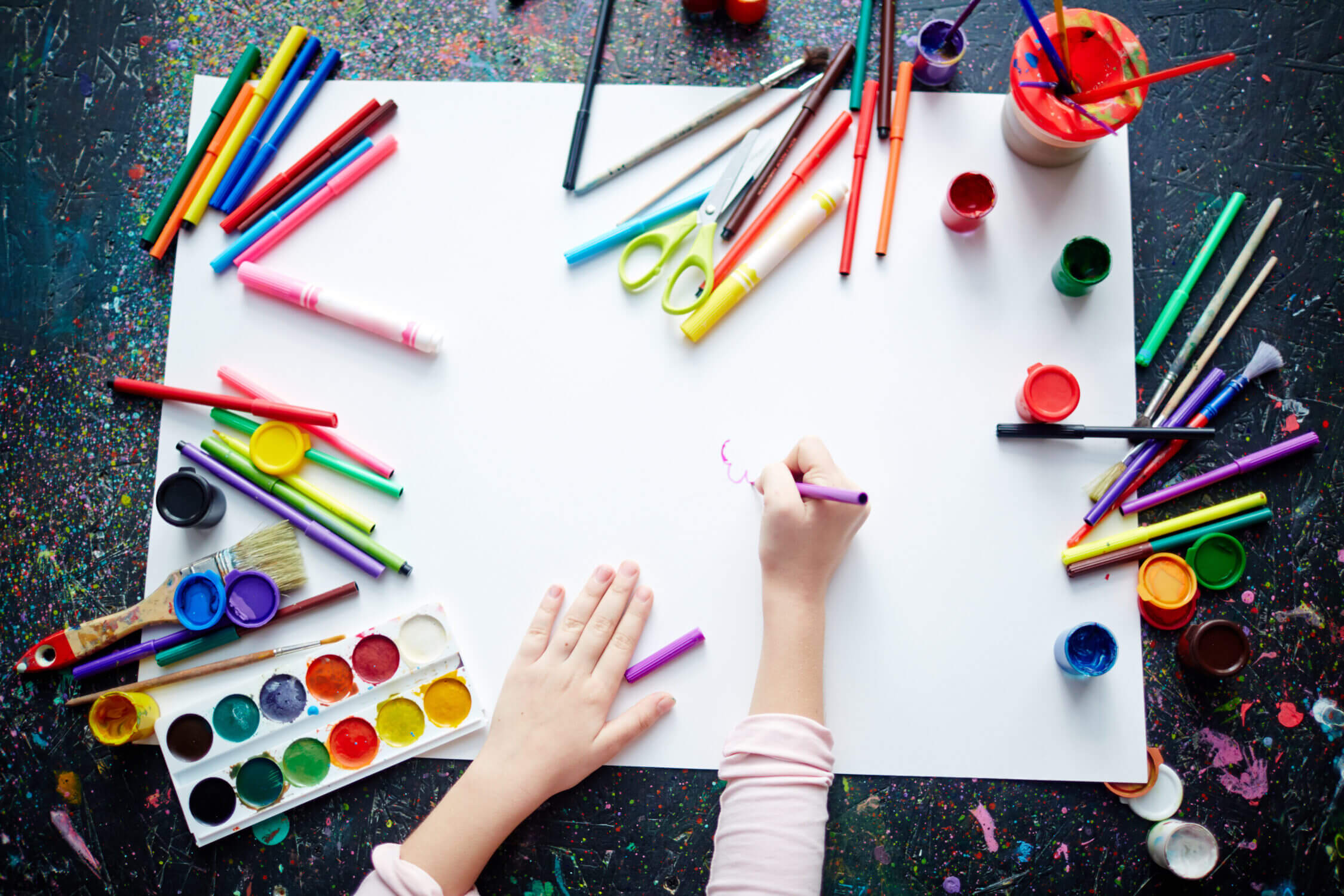 A close-up of a child’s hands surrounded by vibrant art supplies—paintbrushes, markers, scissors, glue, and colorful paper—captures the joy and creativity of art summer camps. This image represents our blog category highlighting the best art-themed summer camps for kids in Seattle, Bellevue, and surrounding areas. These camps provide young artists with opportunities to explore their imaginations through painting, drawing, sculpting, and mixed media. With supportive instructors and engaging projects, art camps foster self-expression, fine motor skills, and confidence, making them a top pick for families seeking creative and enriching summer experiences.