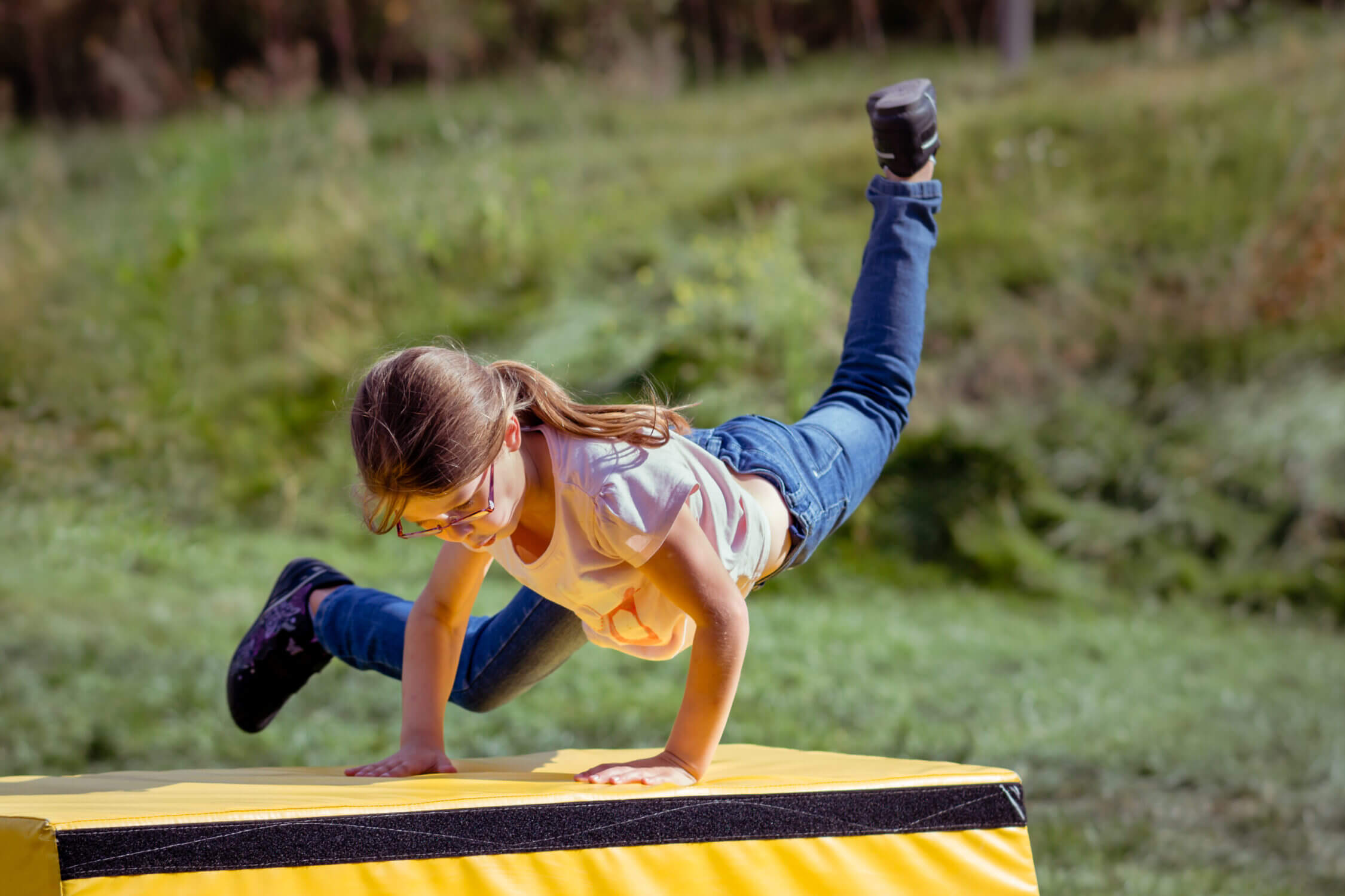 Parkour summer camps for kids offer an exciting way to build strength, agility, and confidence through movement. In this photo, a young girl is mid-jump, using her hands to vault onto a platform—a classic parkour technique that’s taught in a safe and supportive environment. These camps are available throughout Seattle, Bellevue, and surrounding Eastside areas, with experienced instructors guiding campers through obstacle courses, balance challenges, and creative movement drills. Parkour camps not only promote physical fitness but also problem-solving and resilience, making them a thrilling and empowering option for kids of all ages during the summer months.