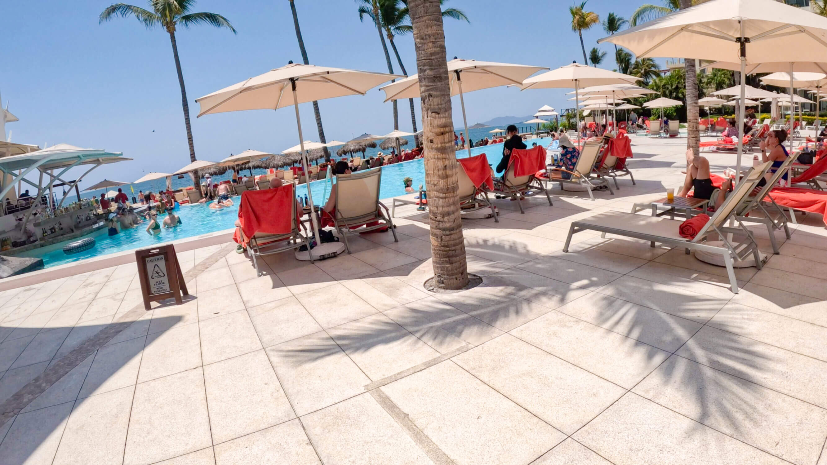 Beachfront pool at Dreams Puerto Vallarta with a swim-up bar at one end, perfect for adults and older kids. The pool is deeper and slightly cooler, offering a more relaxed vibe right next to the ocean—ideal for families looking for a scenic spot to unwind during their all-inclusive vacation.