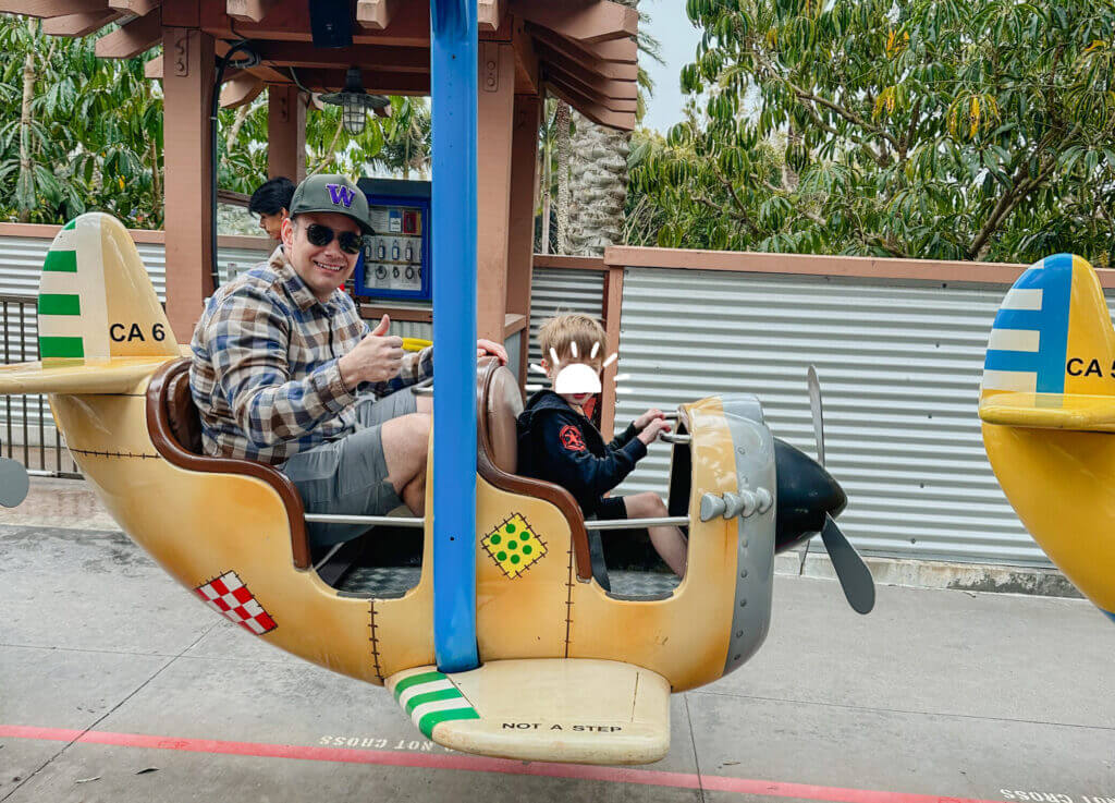 Dad and son enjoying the toddler-friendly Cargo Ace airplane ride at LEGOLAND California, a gentle spinning ride designed for young kids. With bright LEGO-themed planes and low height requirements, it’s one of the best attractions for preschoolers at the park, making LEGOLAND a top destination for families with little ones.