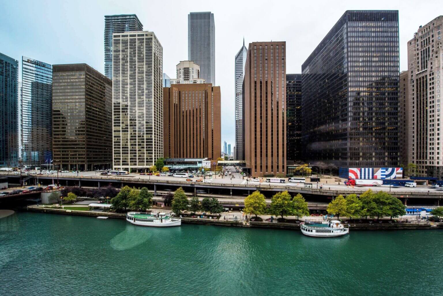 Exterior view of the Hyatt Regency Chicago on a sunny day, with the Chicago River and Riverwalk just steps away. The modern glass-fronted hotel stands tall in the Loop neighborhood, making it a prime location for families visiting Chicago.