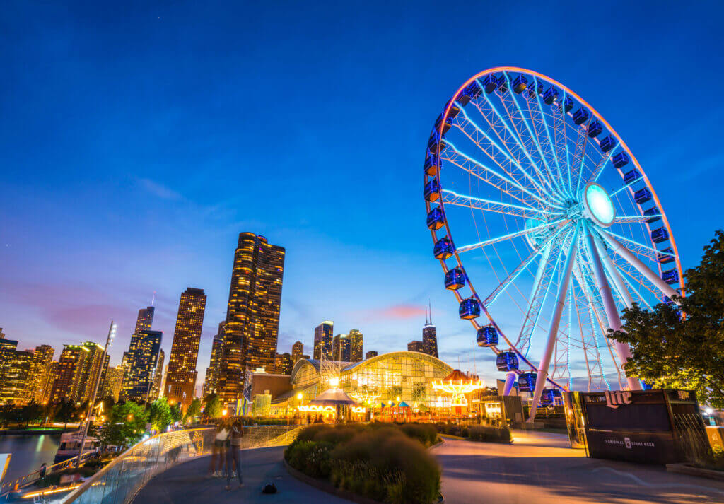 Navy Pier at night in Chicago with the skyline lit up in the background and the Ferris wheel glowing brightly—one of the top attractions for families visiting the city with kids.