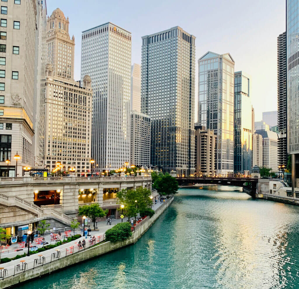 A scenic view of the River North neighborhood in Chicago, featuring the iconic Chicago Riverwalk with towering high-rises and renowned architecture lining the water—showcasing the city’s urban beauty and walkability.