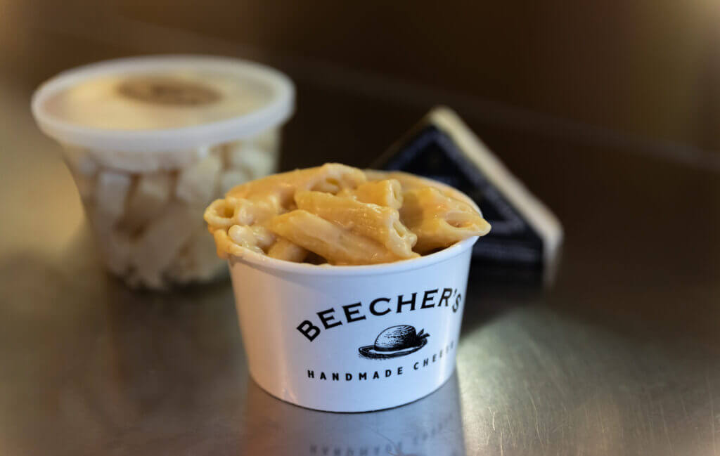 Close-up of a hot cup of Beecher’s famous mac and cheese alongside fresh cheese curds, enjoyed right outside the Pike Place Market shop—one of our favorite kid-friendly food stops in Seattle.