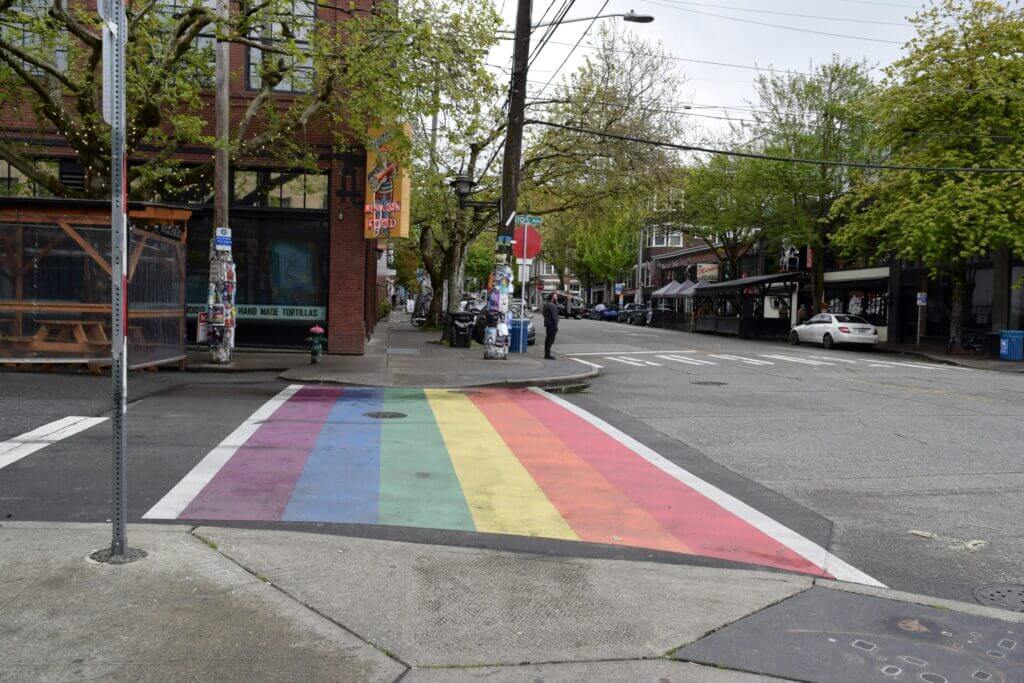 Capitol Hill in Seattle, known as the city’s LGBTQ+ epicenter, featuring a vibrant rainbow-painted crosswalk surrounded by shops and cafes—a colorful and inclusive neighborhood great for exploring with kids.