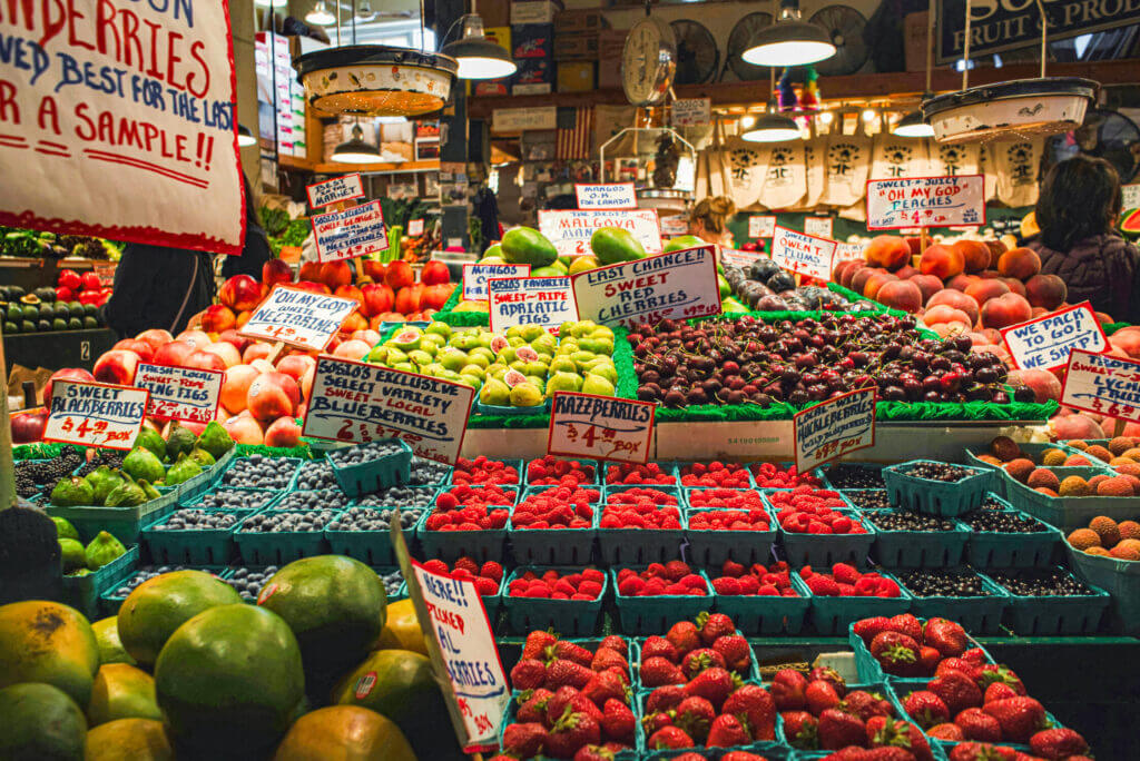 Vibrant fresh fruit stand at Pike Place Market bursting with colorful produce like apples, berries, and peaches—fun for kids to explore and taste while walking through one of Seattle’s most iconic attractions.